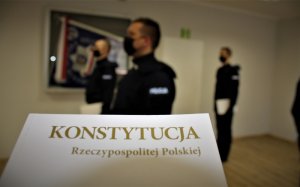 konstytucja Rzeczypospolitej Polskiej a w tle stoją policjanci składający rotę ślubowania