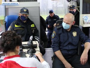 Dwóch mężczyzn siedzi w mobilnym punkcie poboru krwi i ubrani są w mundury straży miejskiej.