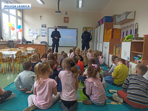 Dwóch policjantów w maseczkach w klasie z dziećmi.