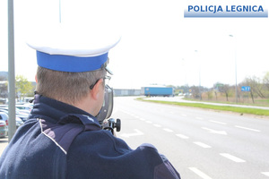 policjant dokonujący pomiar prędkości ręcznym miernikiem prędkości