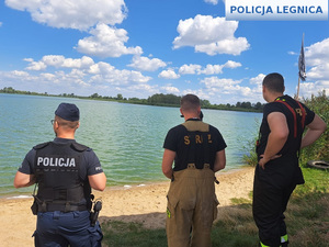 policjant i strażacy nad jeziorem