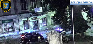 na drodze stoi policyjny radiowóz z włączonymi sygnałami. przed nim stoi drugi pojazd.