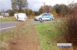 za jezdnią po lewej stronie stoi biały samochód dostawczy a po prawej radiowóz policyjny, na jezdni rozrzucona ziemia określająca tor jazdy pojazdu