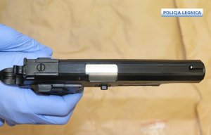 pistolet w dłoni z niebieską rękawiczką, rzut z góry