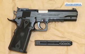pistolet w kolorze czarnym leży na lewym boku pod lufą wypięty magazynek