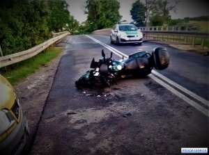 motocykl przewrócony na jezdni a za nim radiowóz policyjny