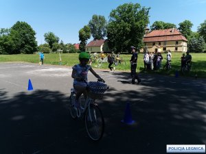 dziewczynka jedzie na rowerze po torze rozstawionym na boisku szkolnym